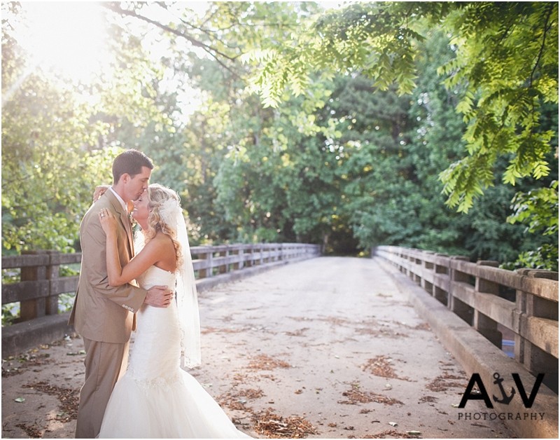 Romantic, emotional sun flare photo with the bride and groom on the bridge at the WInmock at Kinderton in WInston Salem