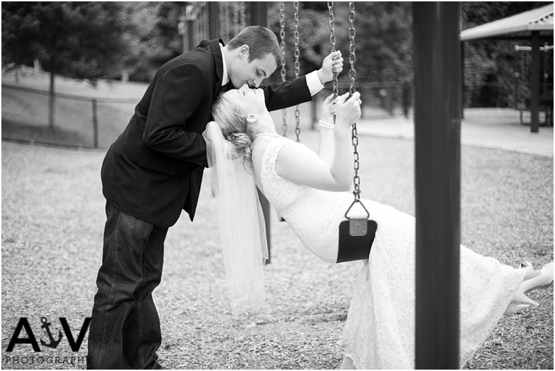 Bride kissing the groom upside down on the swing after the wedding ceremony at the summerfield amphitheater in north carolina