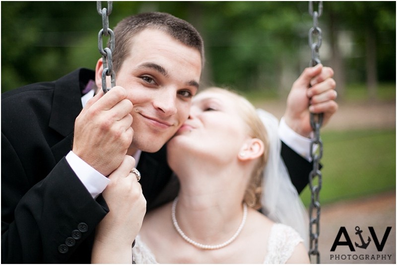 Bride kissing the groom on the cheek on the swing after the ceremony at the summerfield amphitheater