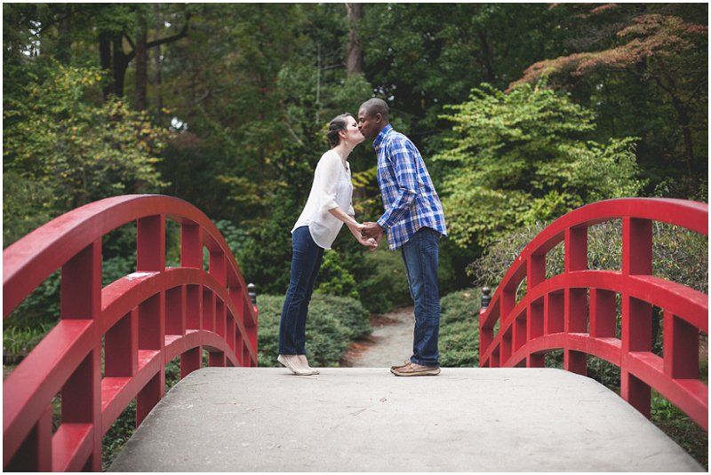 Kissing on the red bridge at the Duke Gardens during the engagement session
