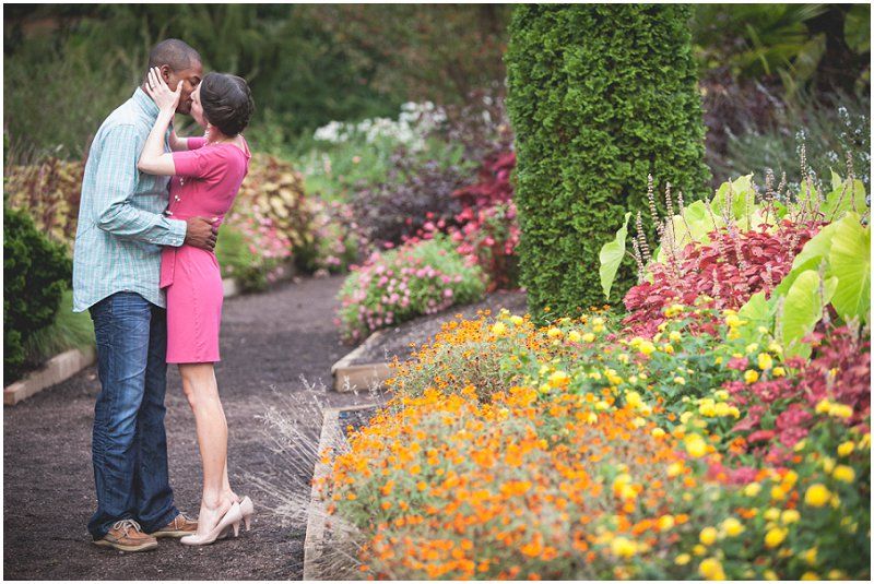 Kissing near the flower patch during the engagement session at the duke gardens in a pink dress