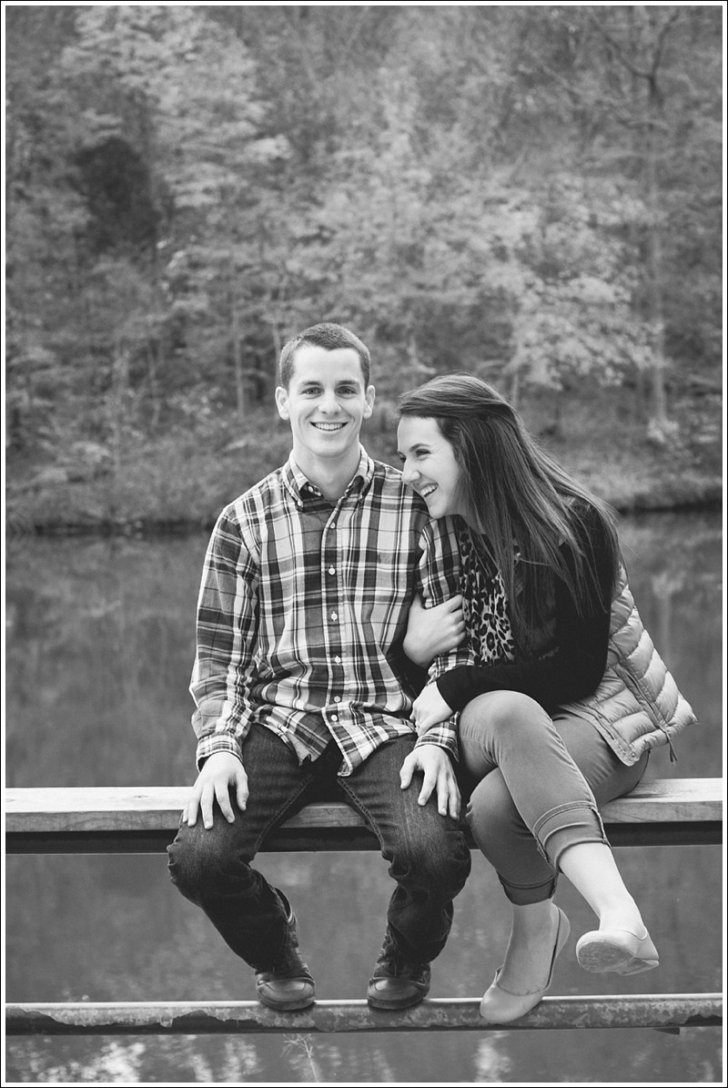 A genuine look of love over the dock at the lake during the fall engagement session at reedy creek park in Charlotte North Carolina