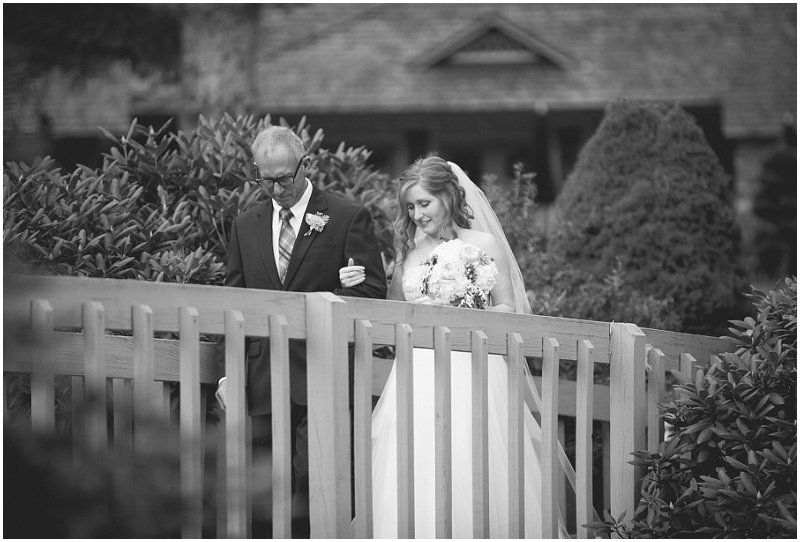 Bride crossing the bridge with her father to the ceremony at the Waterfront wedding at the chetola resort and spa in Blowing rock North Carolina