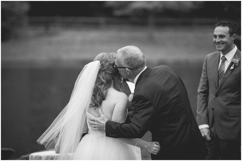 Father kissing his daughter on the cheek during the Waterfront wedding at the chetola resort and spa in Blowing rock North Carolina