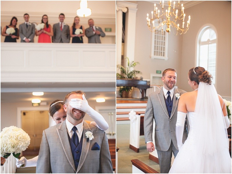 The first look with the bride covering his eyes in the church with the bridal party in the balcony during the High Point North Carolina Wedding at First Baptist Church High Point and high point country club at Emerywood