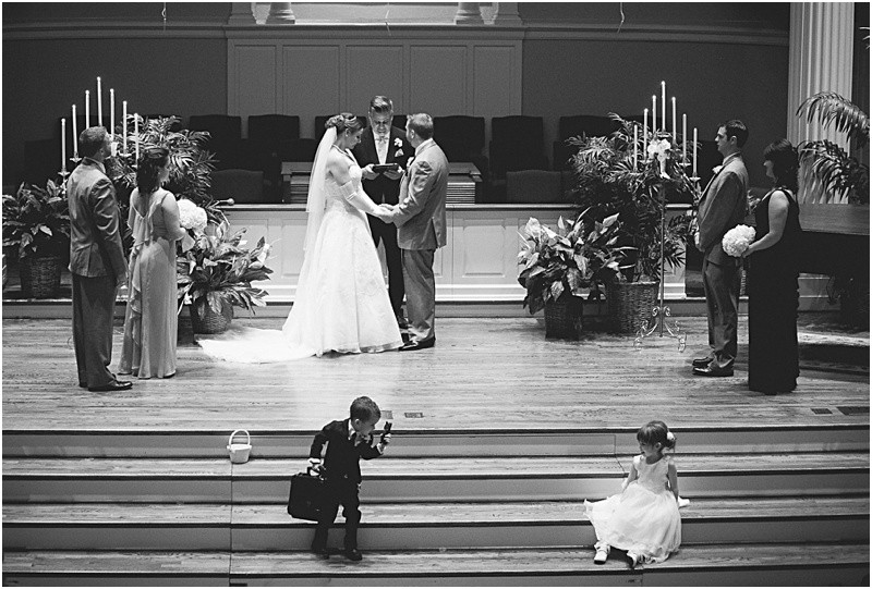 The ring bearer and the flower girl playing during the wedding ceremony during the sparkler exit with a fur wrap during the High Point North Carolina Wedding at First Baptist Church High Point and high point country club at Emerywood
