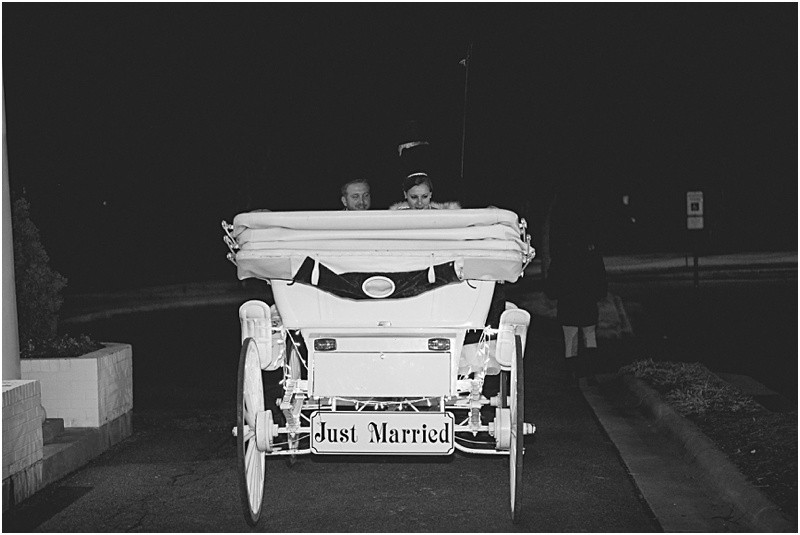 Driving away in the horse and carriage with the just married sign during the sparkler exit with a fur wrap during the High Point North Carolina Wedding at First Baptist Church High Point and high point country club at Emerywood