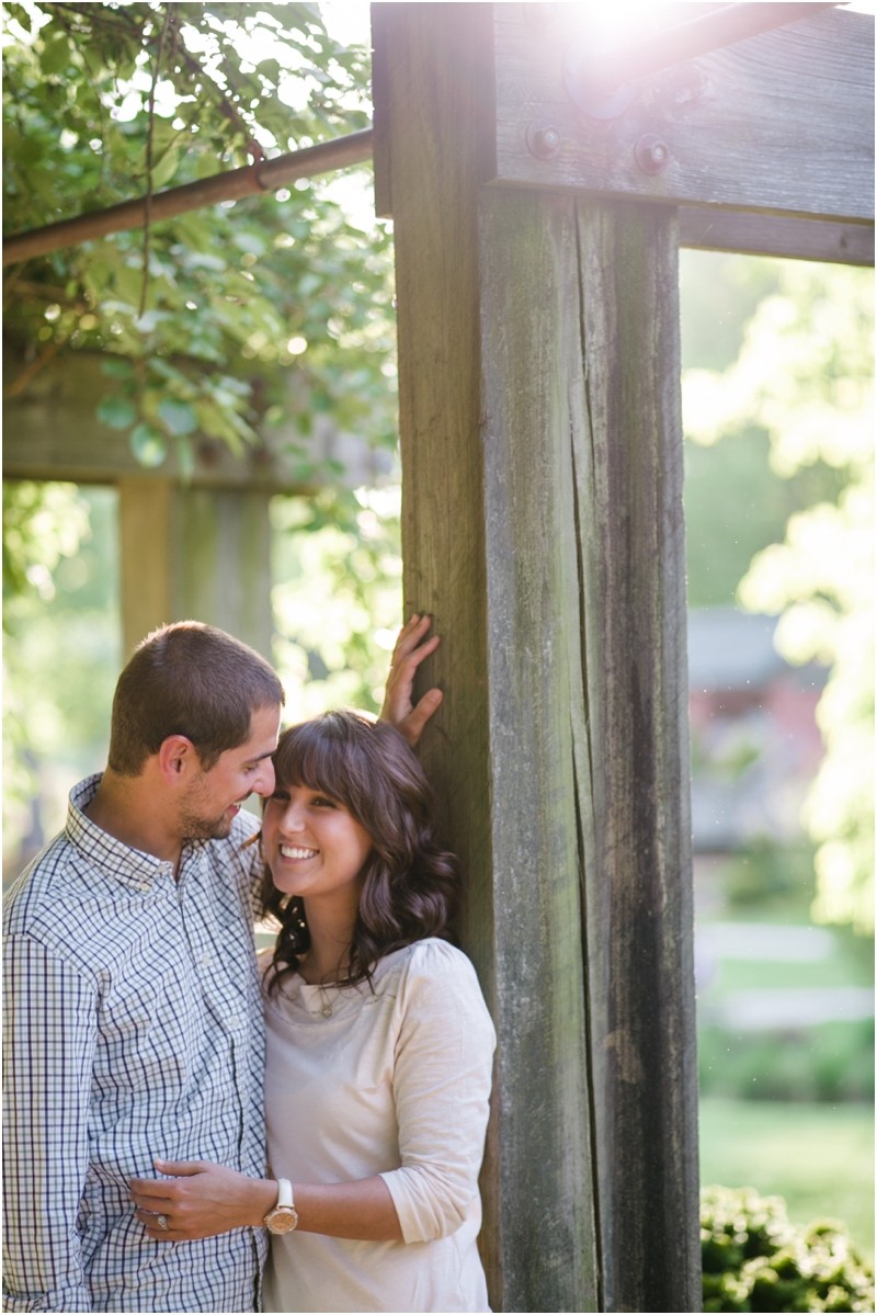under the lattice walkway with the sun peeking out at the Greensboro Arboretum gardens engagement session in greensboro north carolina