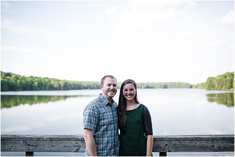 standing on the dock by the lake during the engagement session at burr mill park and the greensboro bicentennial gardens