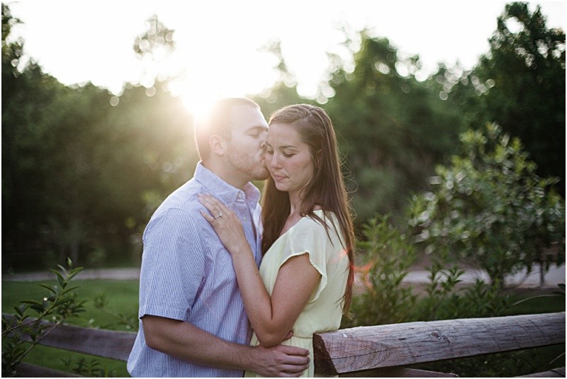 kissing in the sun during the engagement session at burr mill park and the greensboro bicentennial gardens