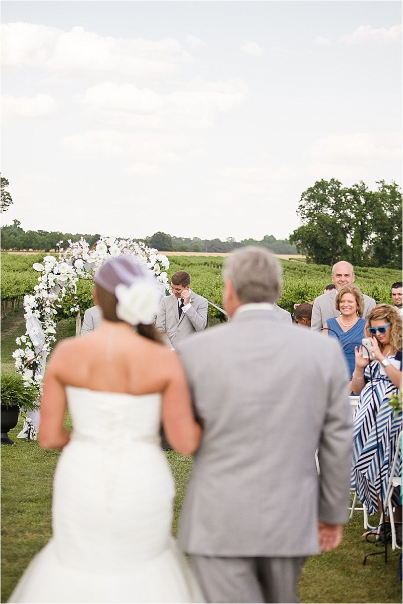 Groom crying as his bride walks down the aisle during the vineyard wedding at the Hinnant Family Vineyard in Pine Level Nc near Raleigh