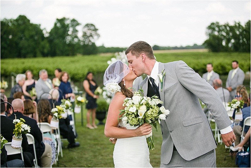 Kissing at the end of the aisle during the vineyard wedding at the Hinnant Family Vineyard in Pine Level Nc near Raleigh