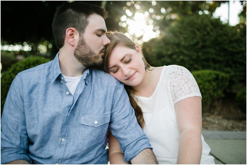 groom kissing her as she leans on his shoulder at the Three River Greenway in Columbia South Carolina During their engagement session
