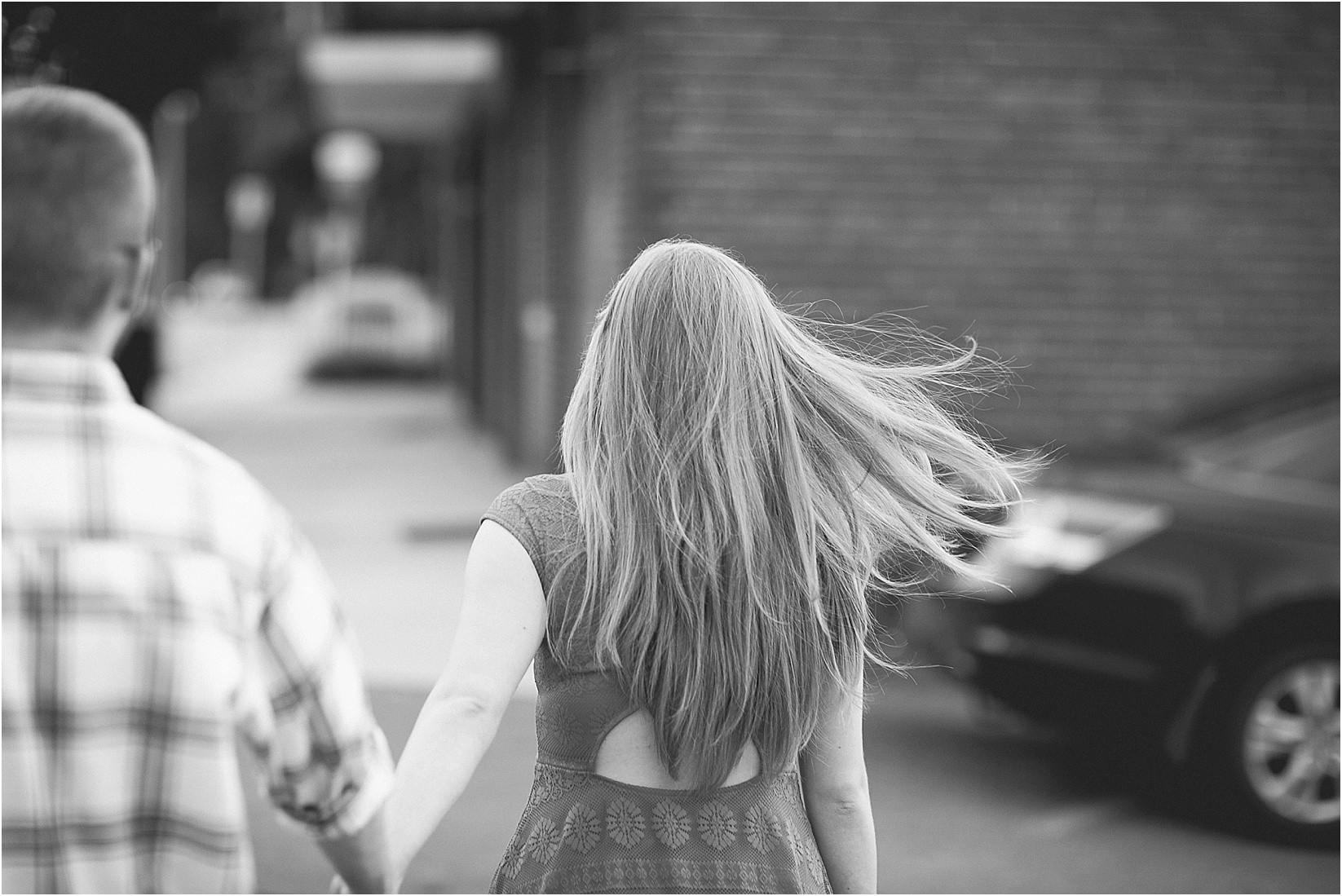 Hair blowing while walking during Andria & Matts Mount Pleasant engagement session in downtown mount pleasant nc