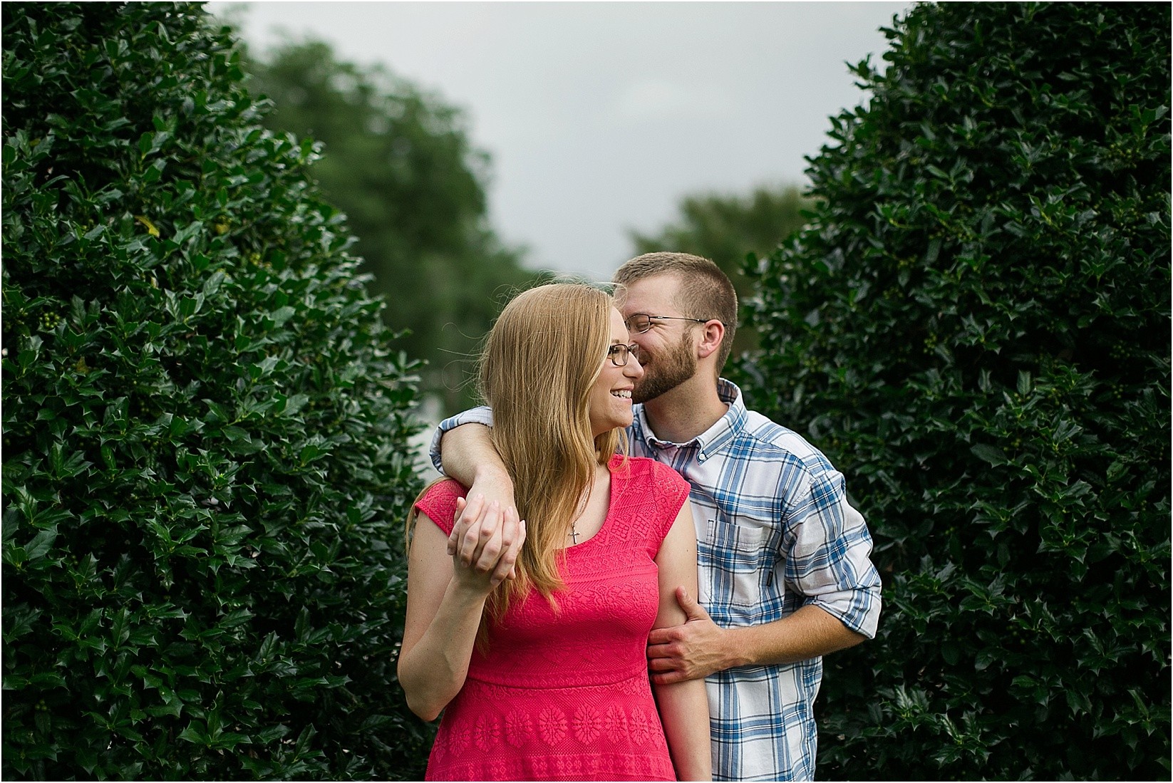 between the bushesduring Andria & Matts Mount Pleasant engagement session in downtown mount pleasant nc
