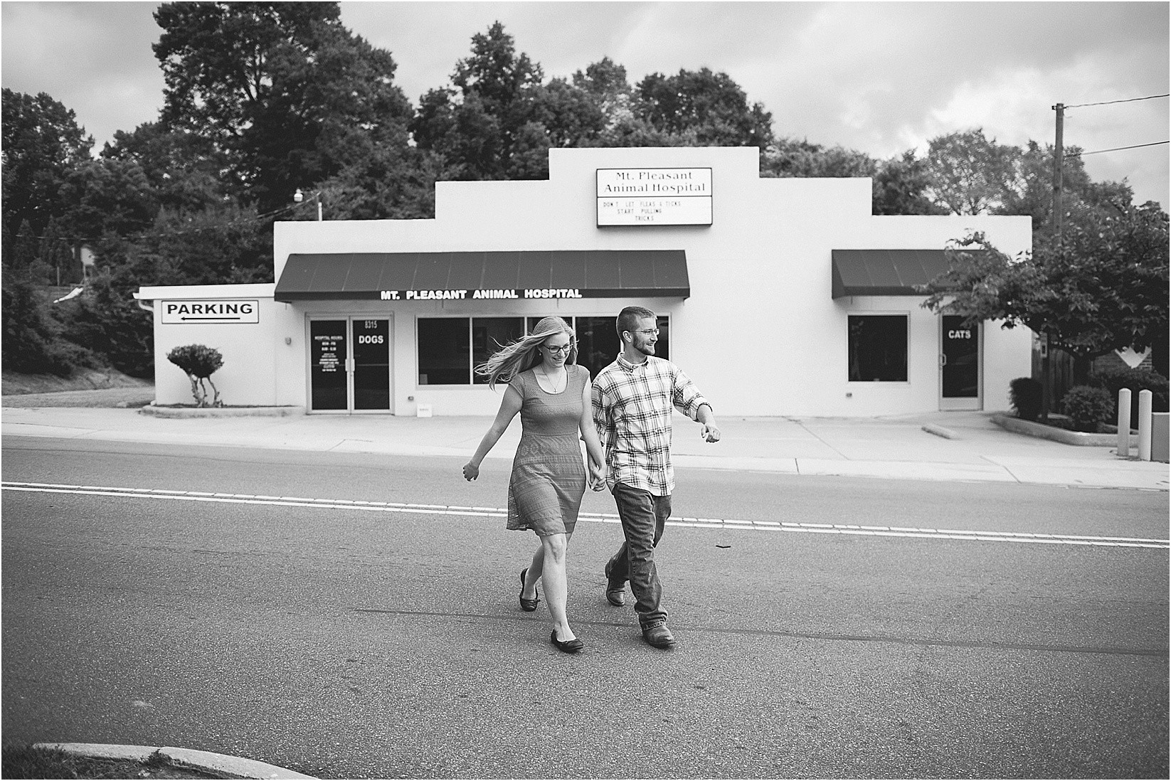 walking across the street during Andria & Matts Mount Pleasant engagement session in downtown mount pleasant nc