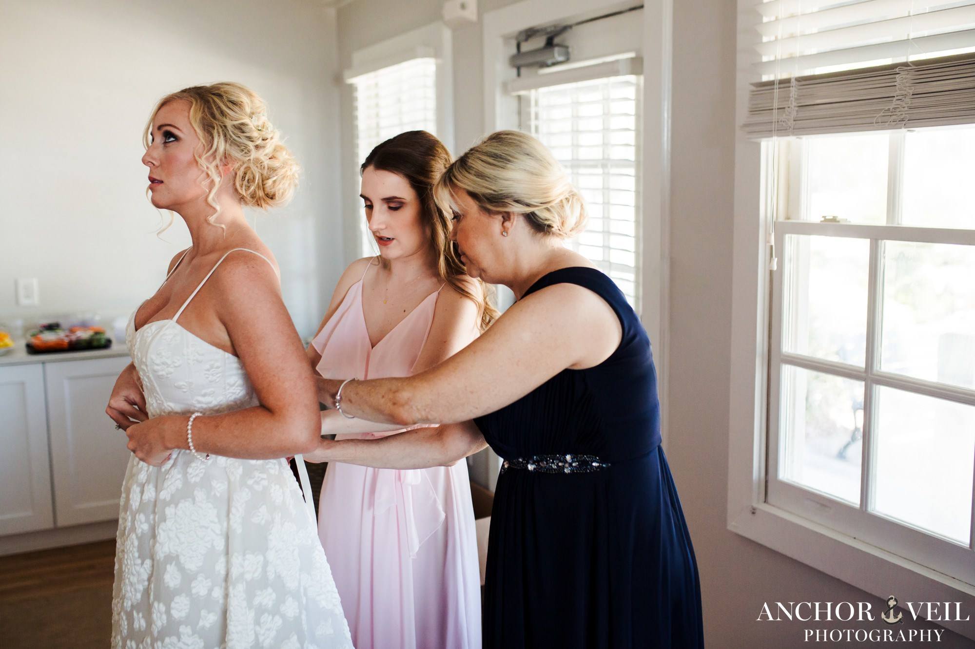 family tying the bow on the back of the brides dress