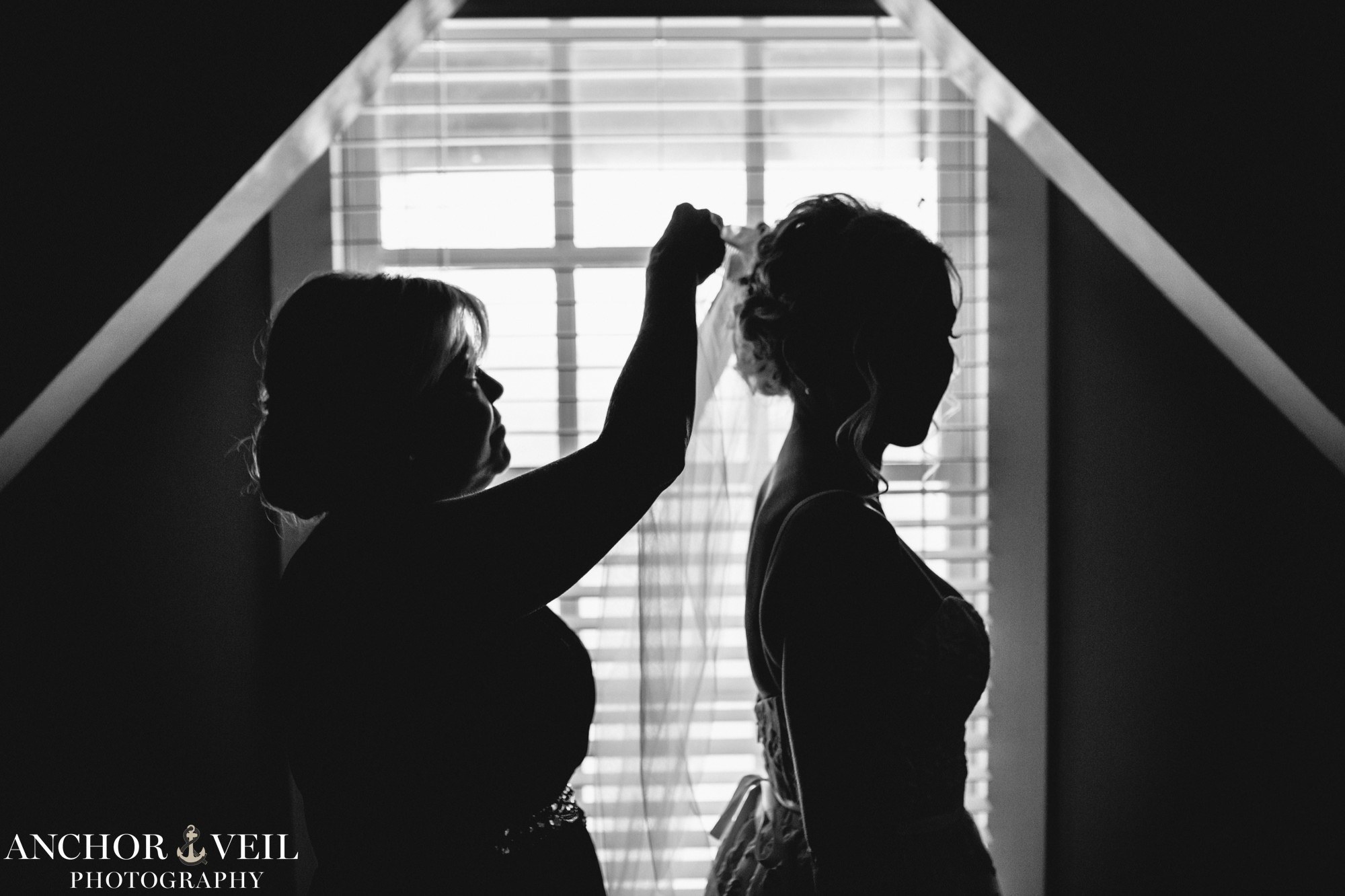 silhouette of mom putting veil on the bride