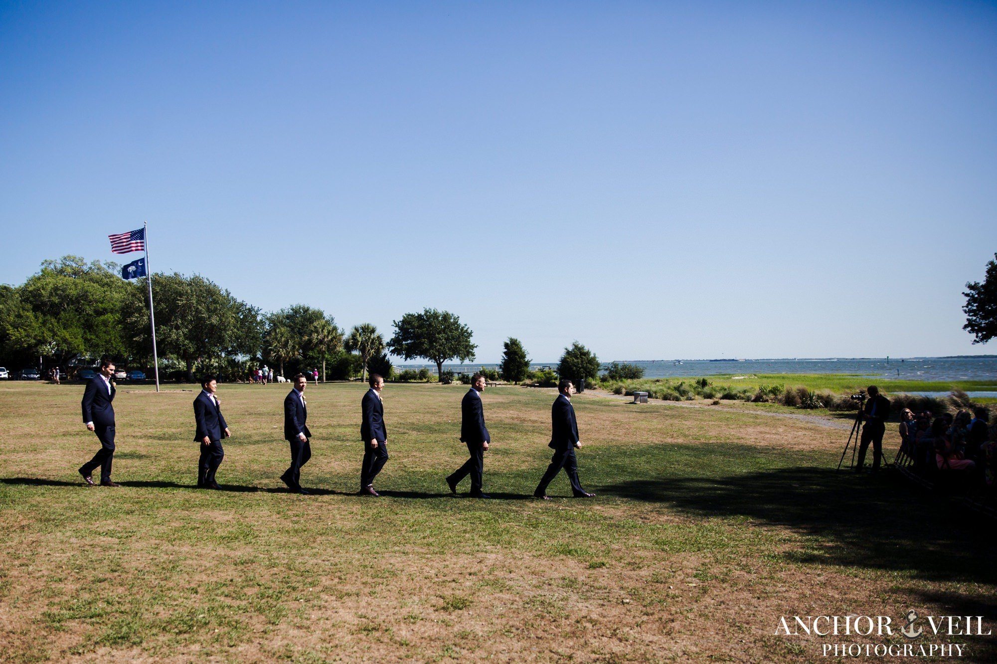groomsmen walking into the ceremony with the charleston harbor in the background