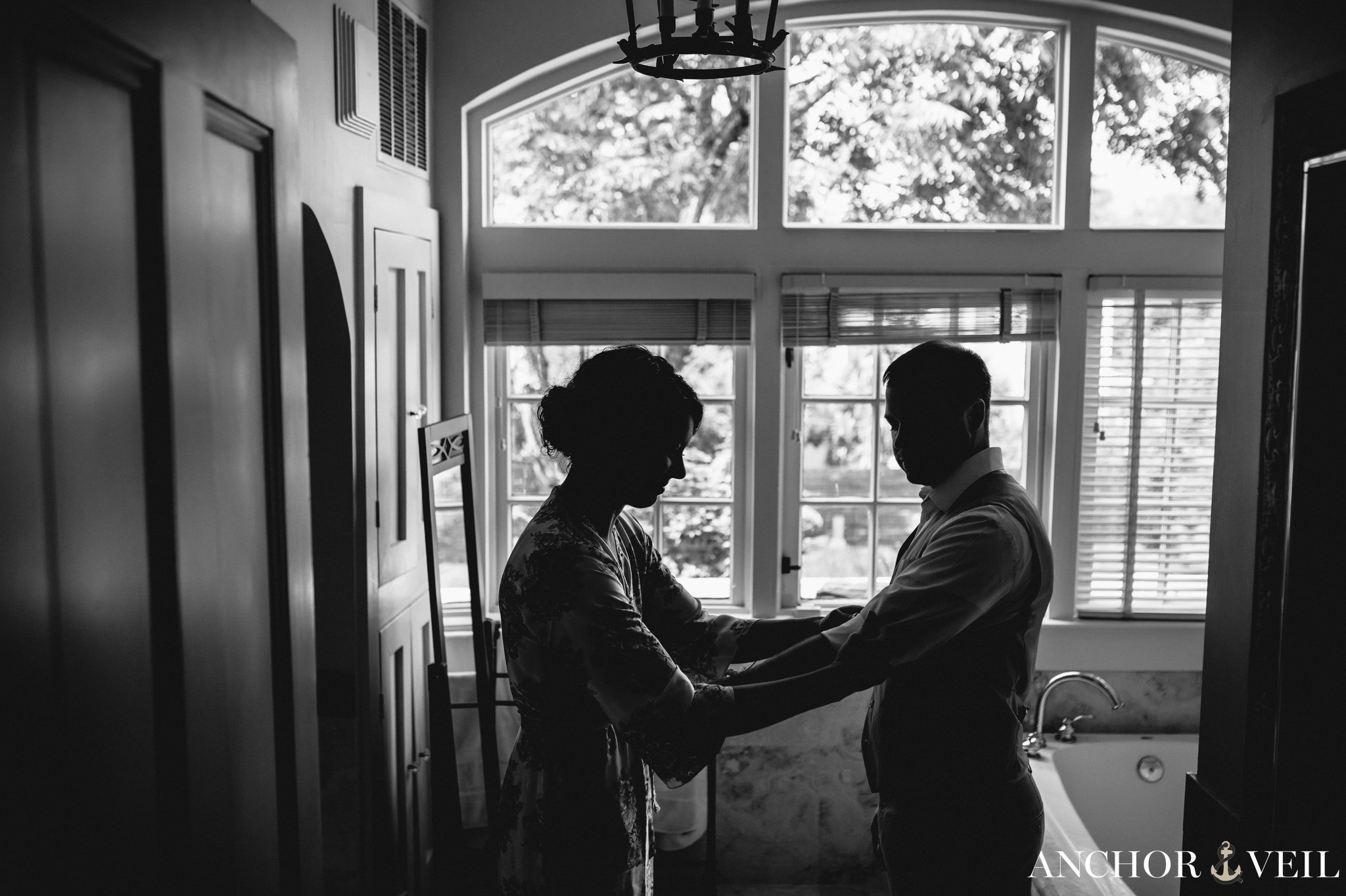 bride helping groom get his sleeves rolled up during their Forsyth Park Wedding Elopement