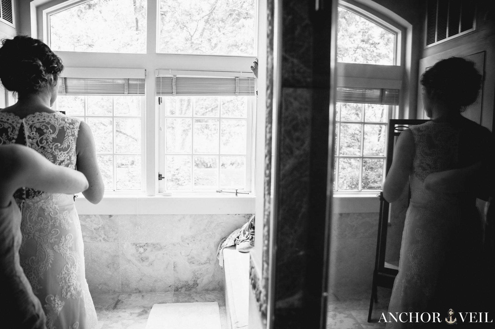 bride getting ready in the bathroom through the mirror