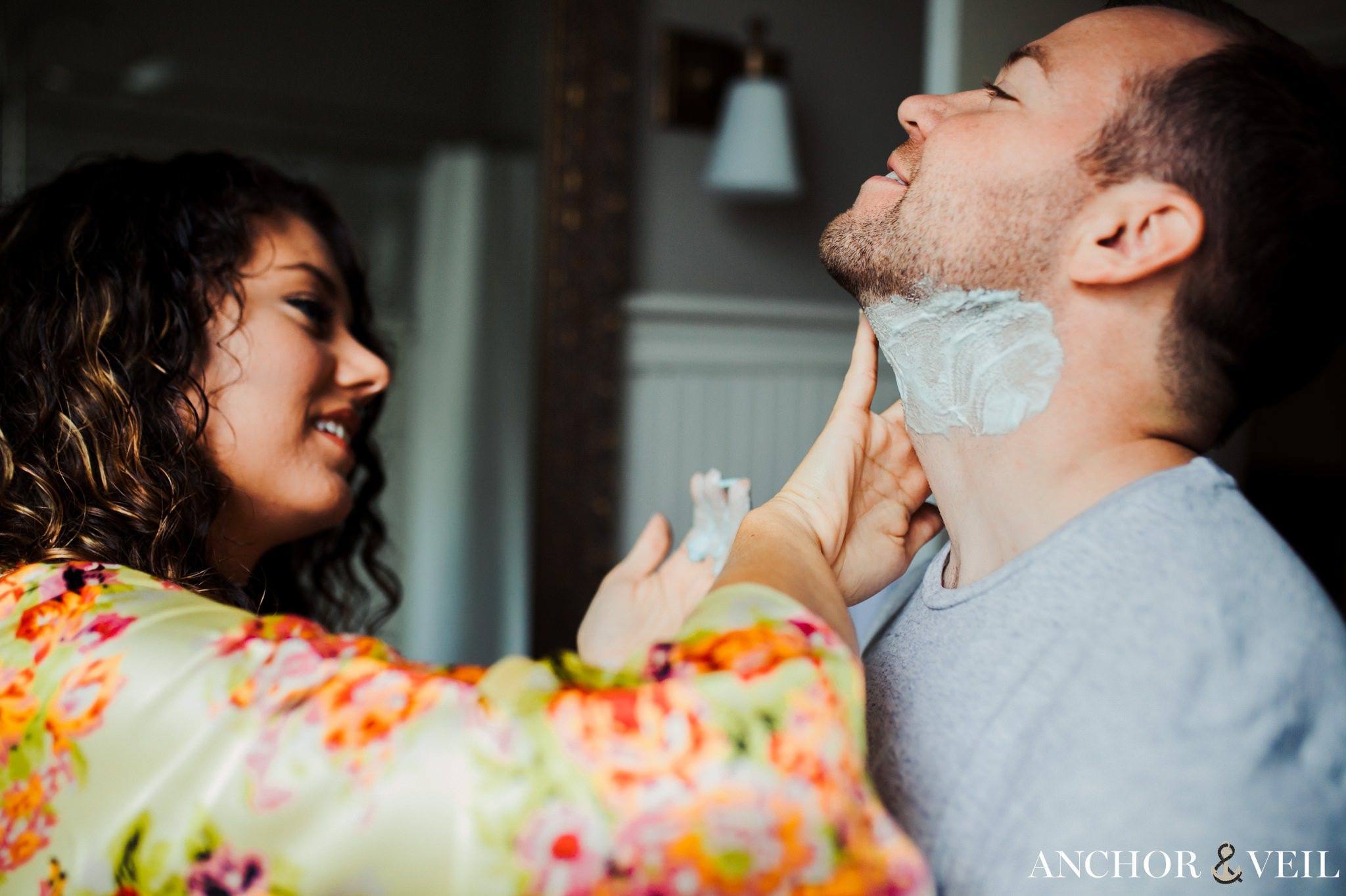 bride helping groom shave before the wedding during their Forsyth Park Wedding Elopement