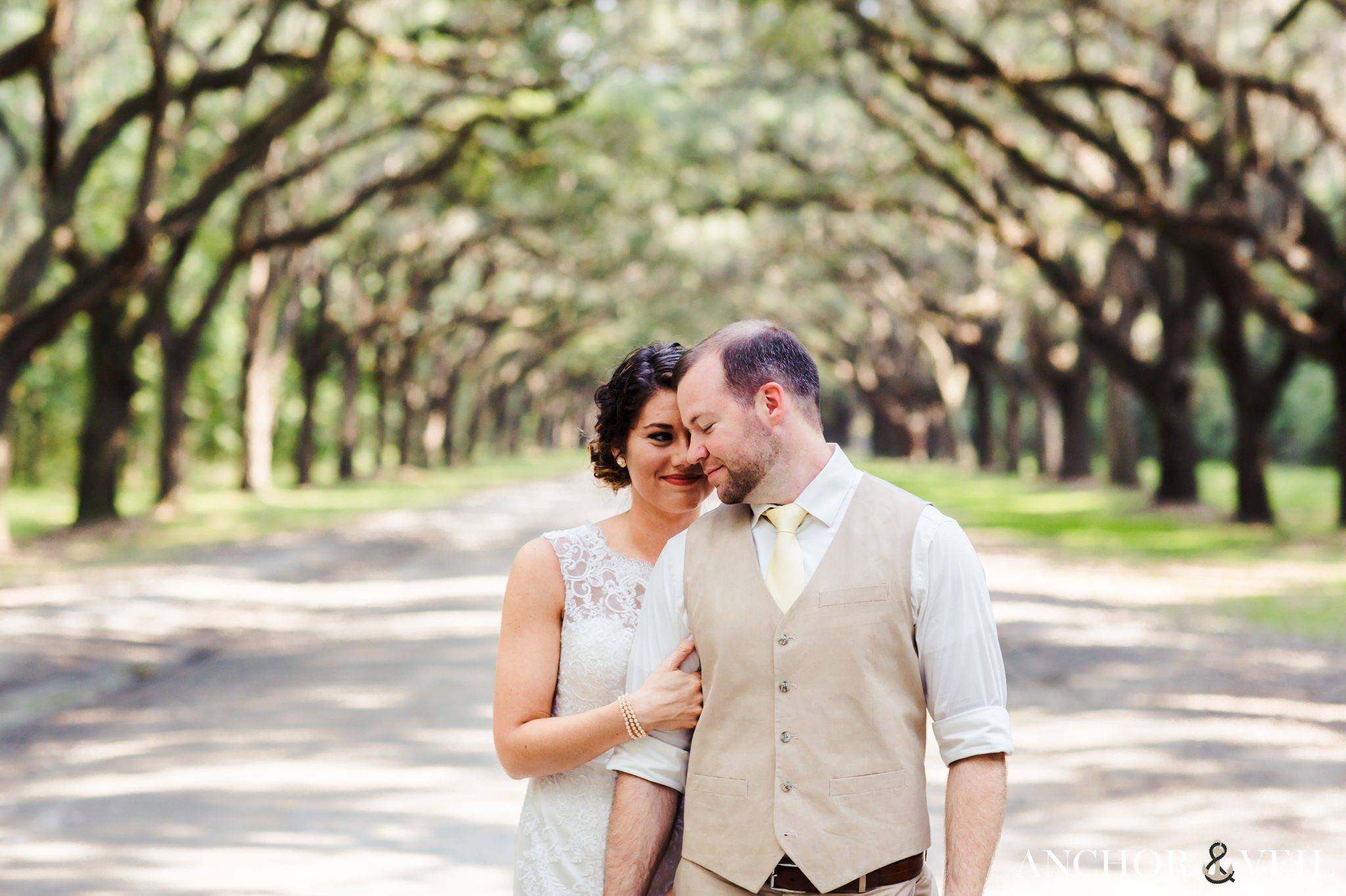 under the trees and holding each other in the middle during their Forsyth Park Wedding Elopement