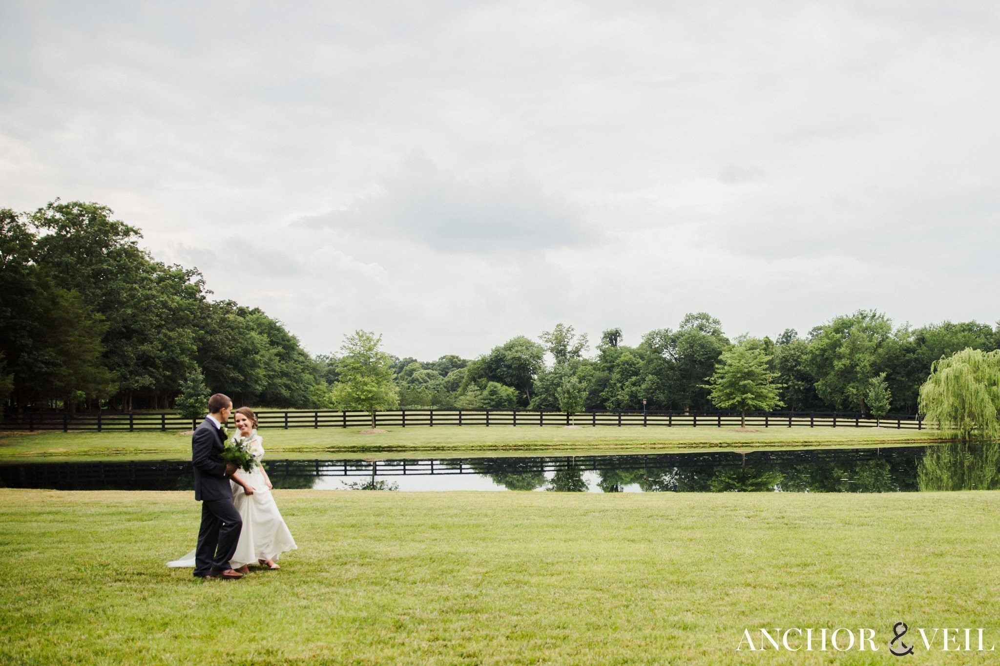 bride and groom walking by the pond at the farm