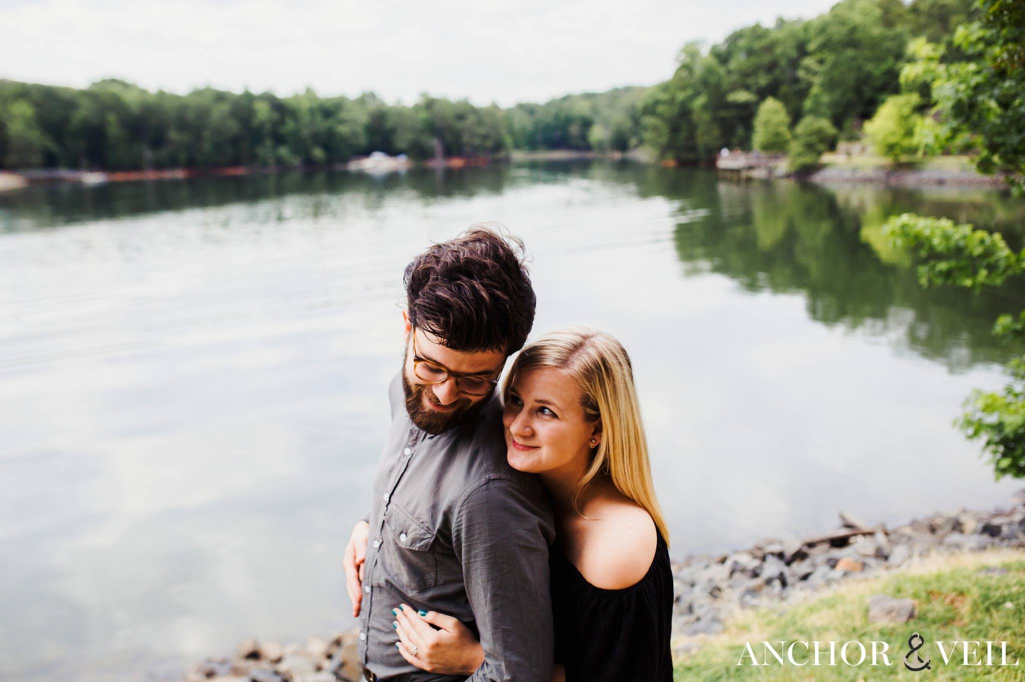 Holding him from behind near the water during their McDowell Nature Preserve Engagement Session