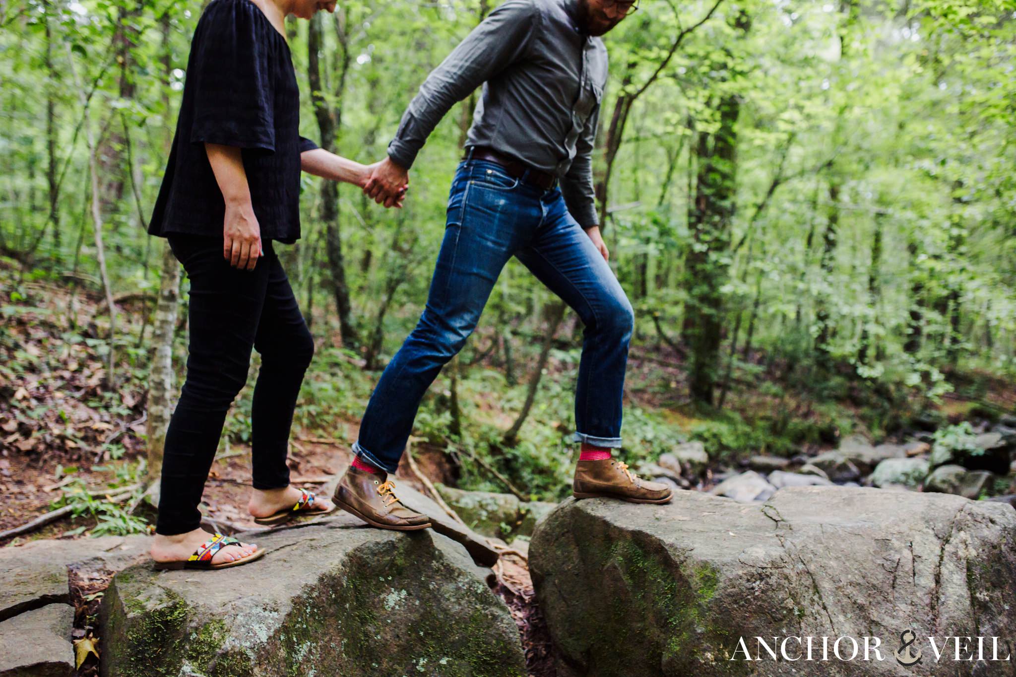walking over the rocks during their McDowell Nature Preserve Engagement Session