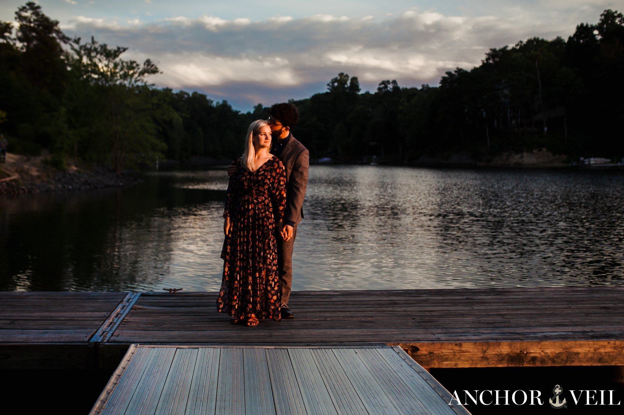 standing on the dock in front of the water at sunset during their McDowell Nature Preserve Engagement Session