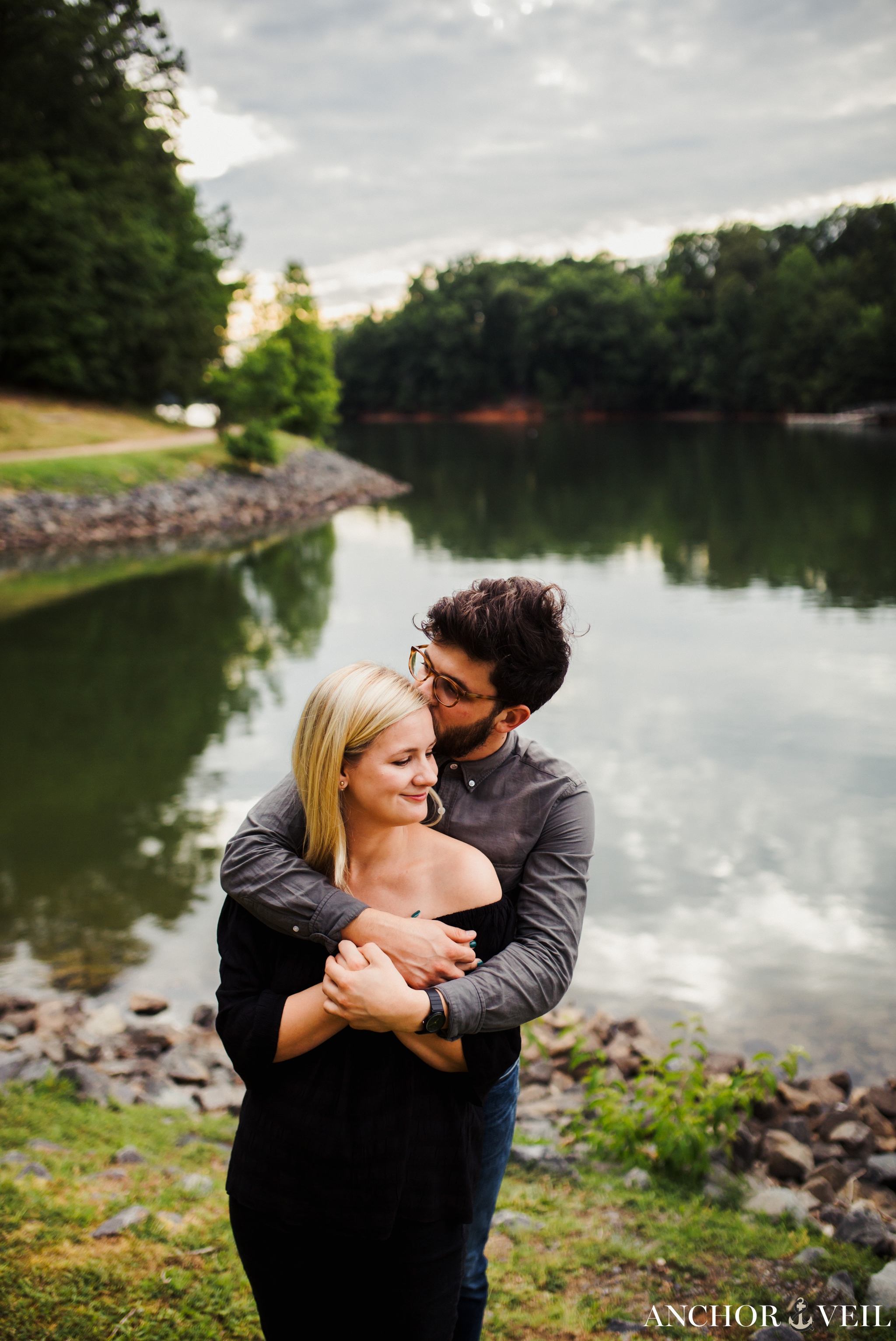 Holding her in front of the water with he light around them during their McDowell Nature Preserve Engagement Session