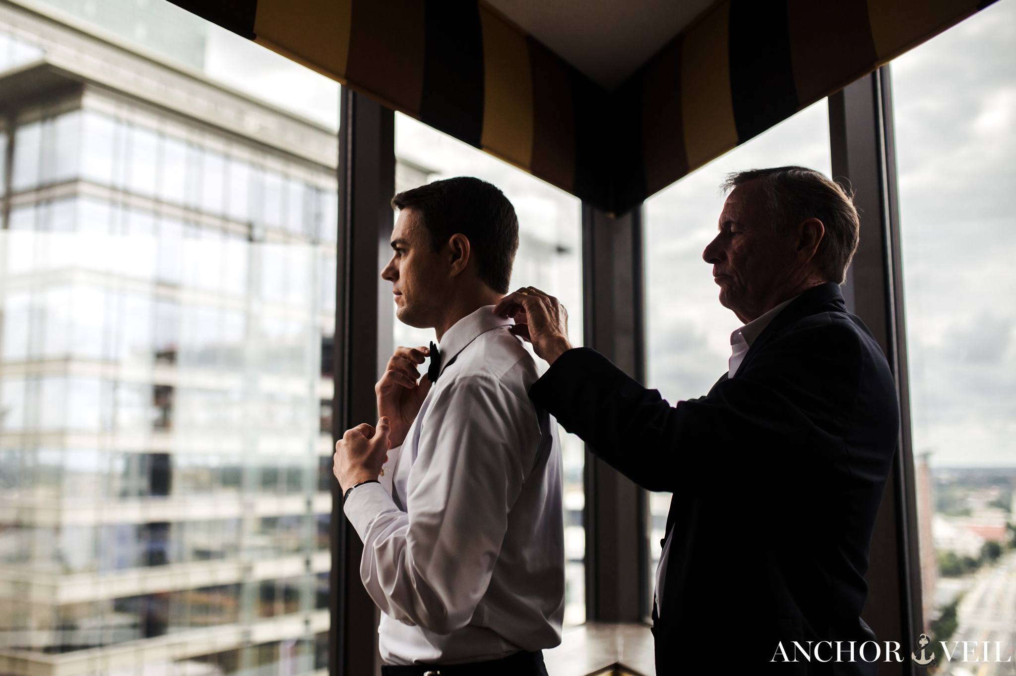 Groom getting ready in the omni hotel uptown charlotte with the buildings in the background