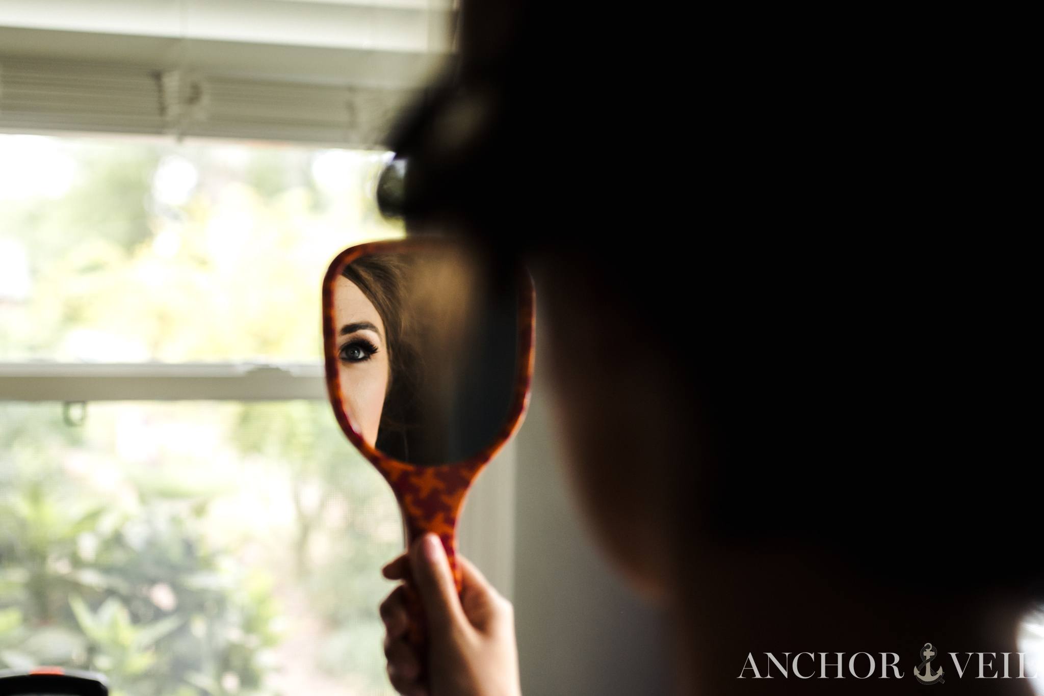 brides eye in the mirror while she gets ready
