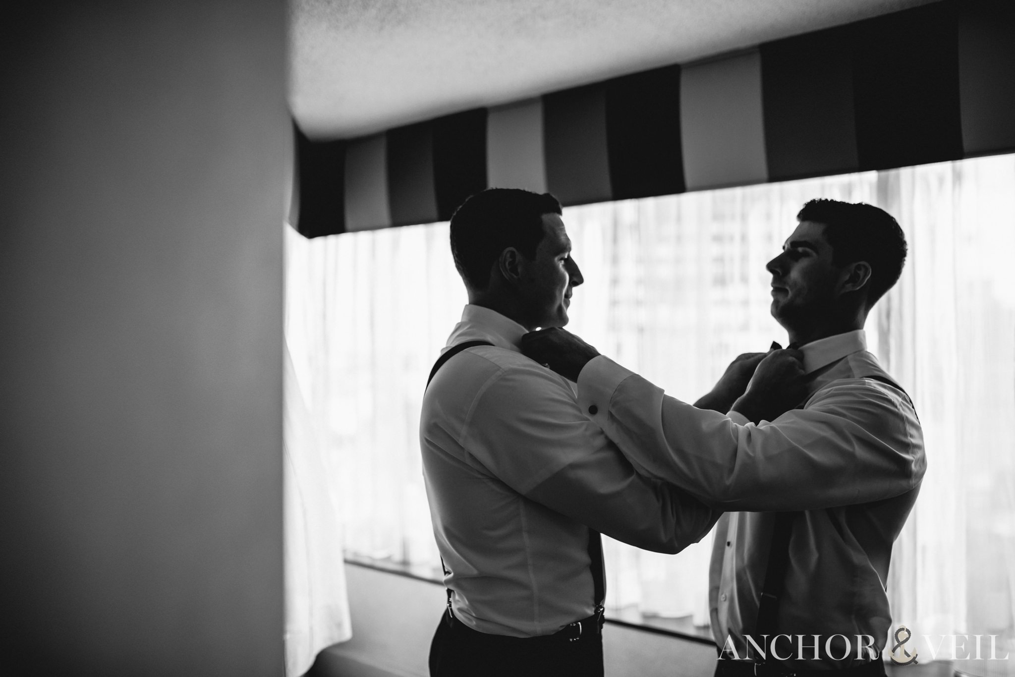 brother helping groom with bowtie at the omni hotel