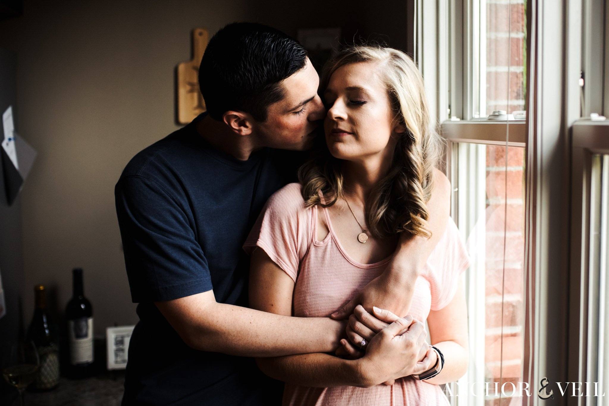 kissing next to the window during the In Home Charlotte Engagement Session