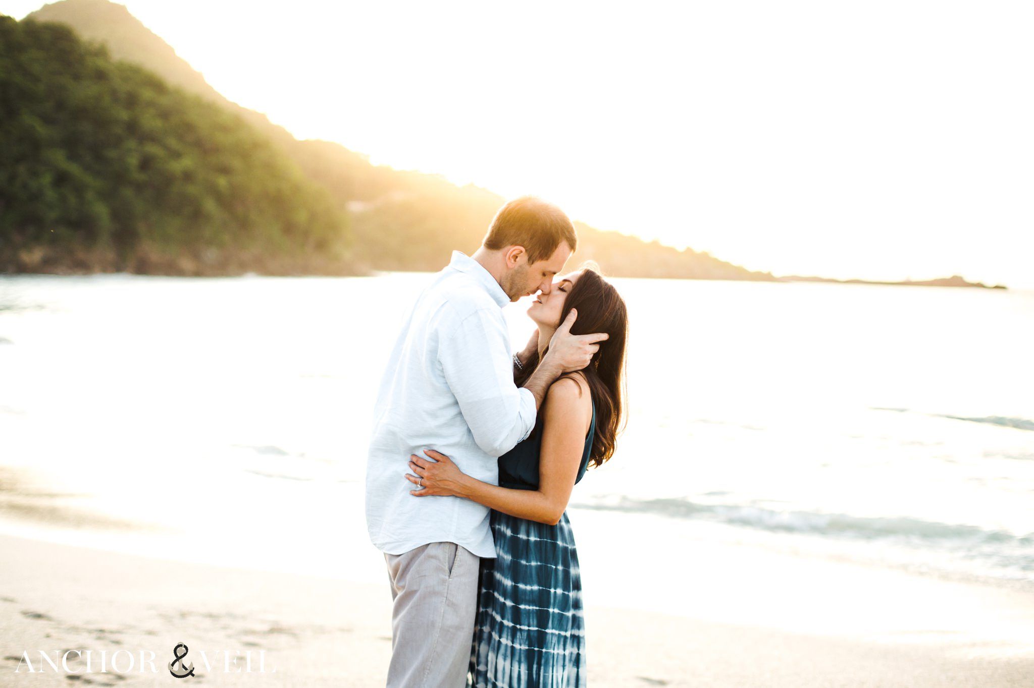 kissing each other near the water at Hermitage Bay wedding Shoot