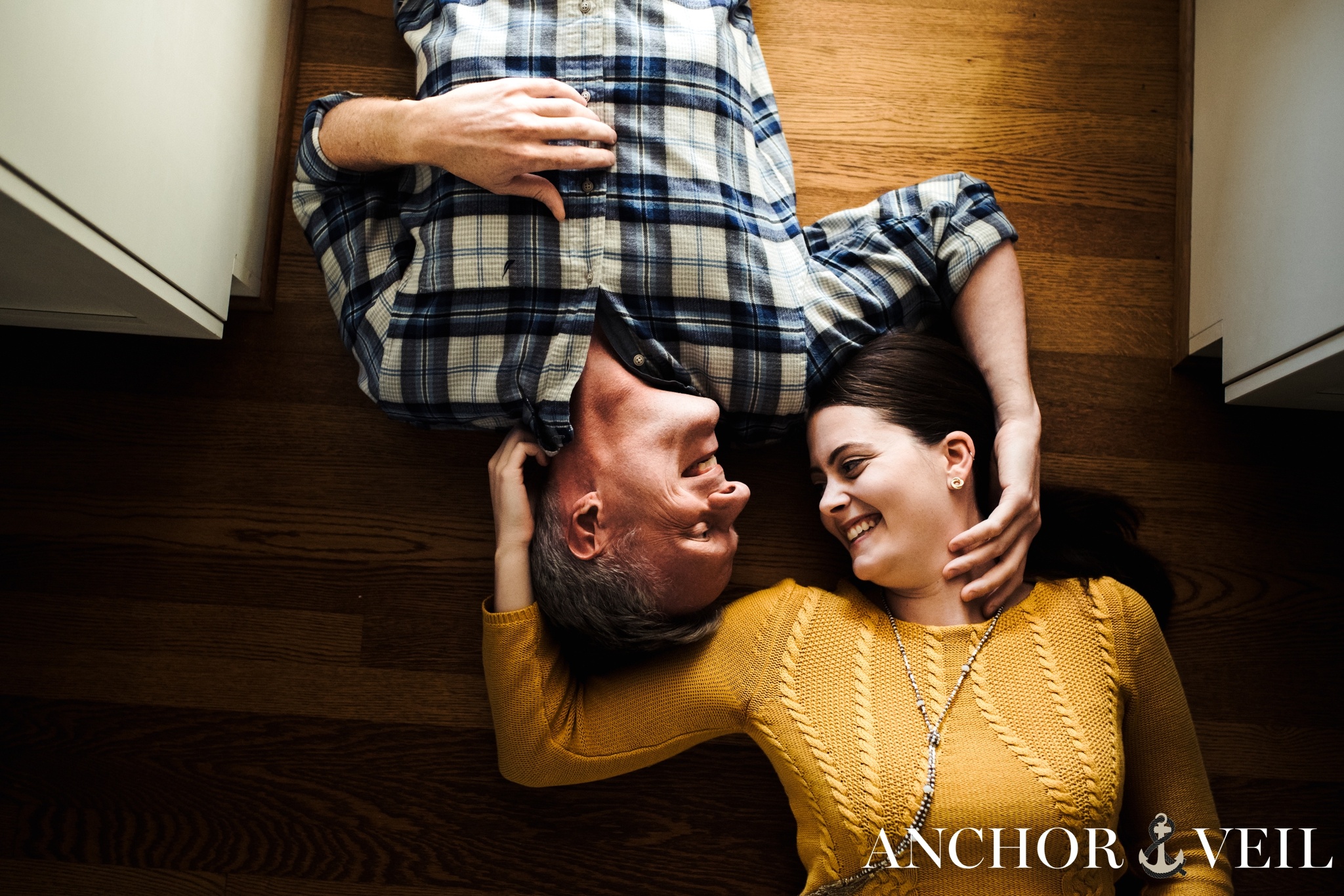 laying on the floor smiling during the in home kitchen engagement session