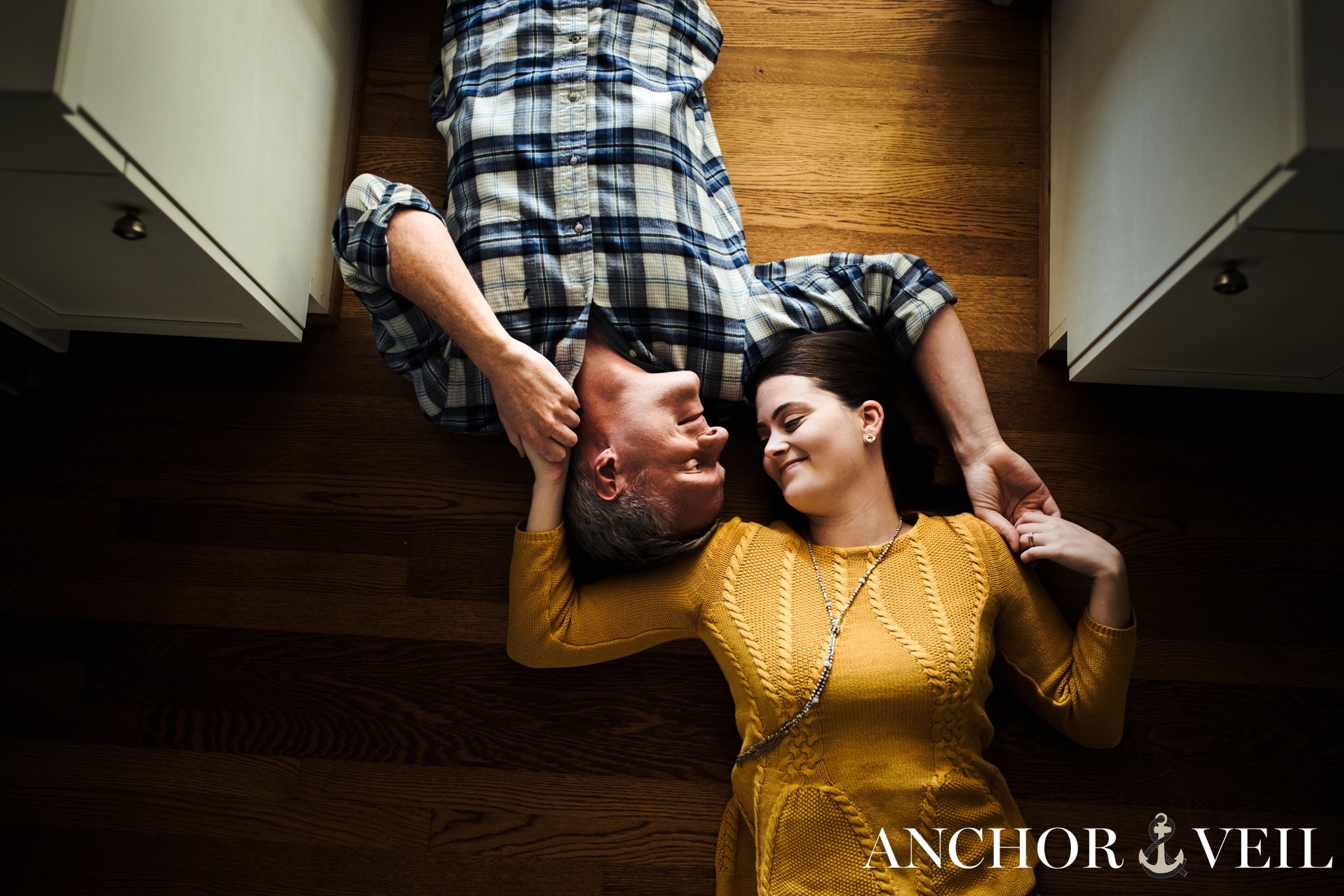 holding hands while laying on the floor during the in home kitchen engagement session