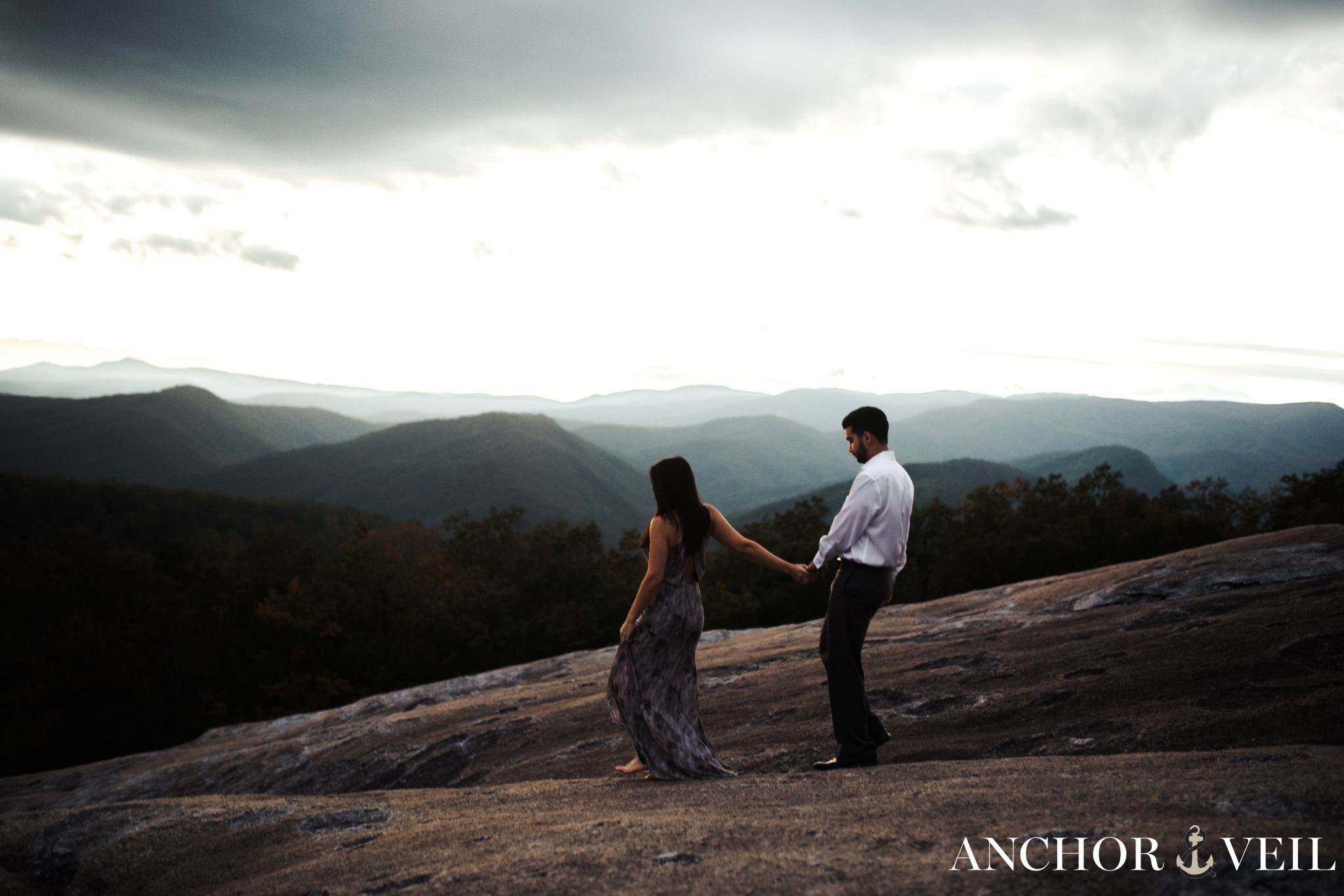 walking hand in hand down the mountain during the Stone Mountain Engagement Session