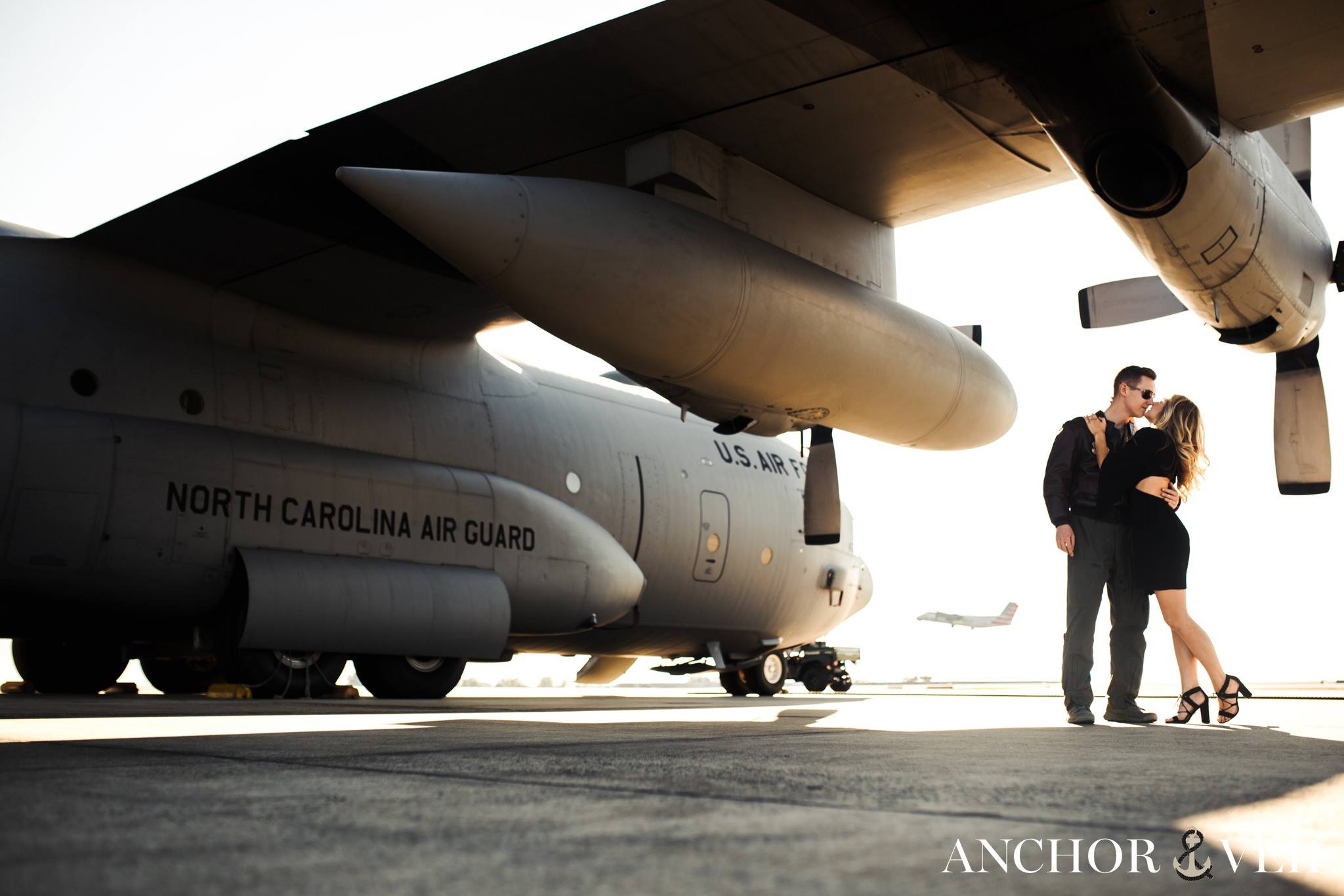 kissing under the plane wing during the aviation themed engagement session in Charlotte NC