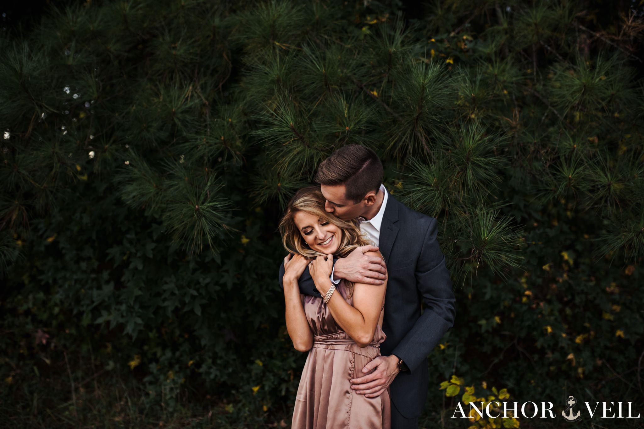 kissing her in the woods in the tree forest during their charlotte engagement session