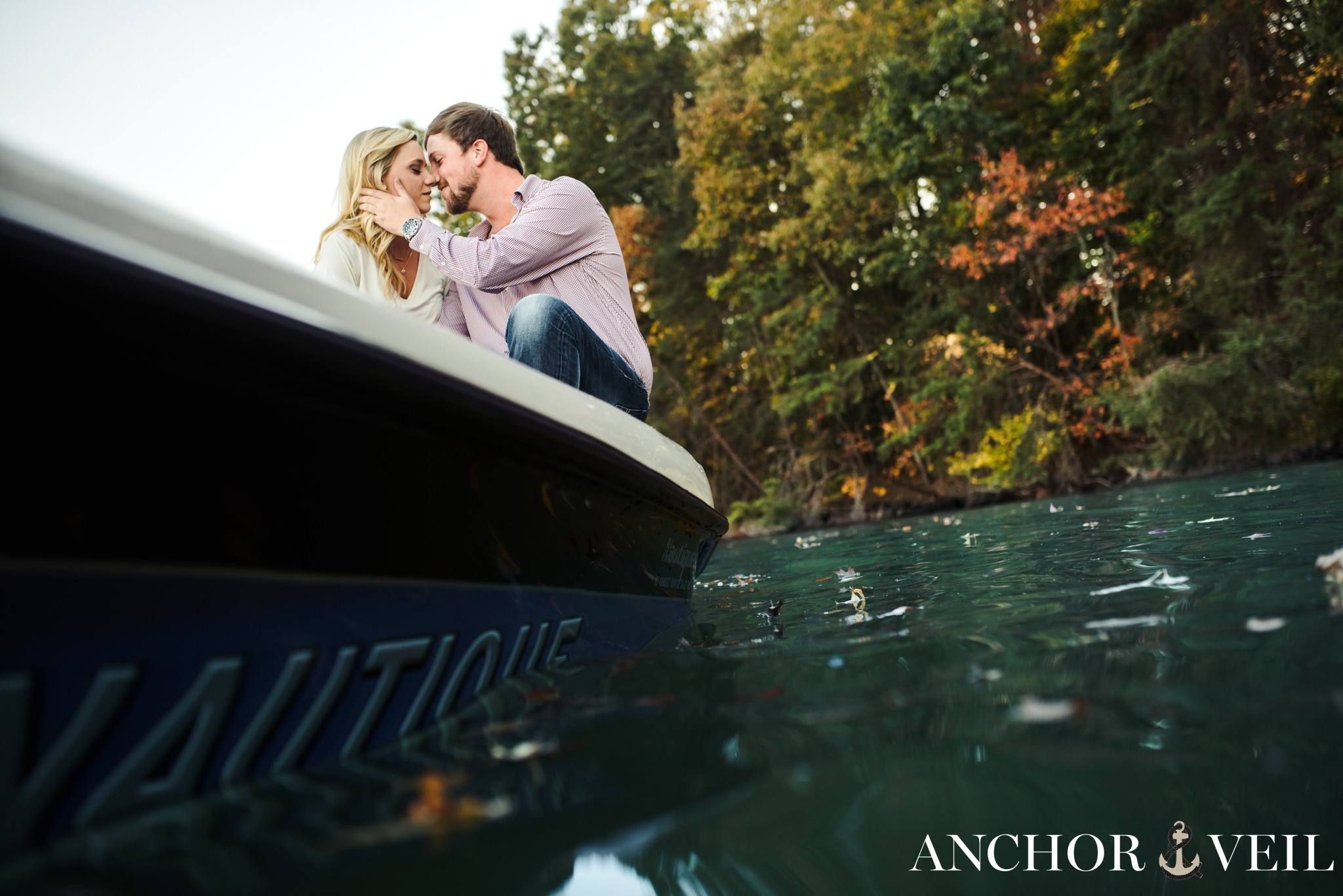 kissing on the back of the boat from in the water during the belews lake engagement session
