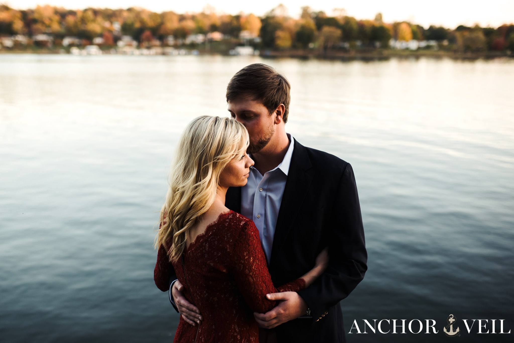 standing near the lake holding each other during the belews lake engagement session