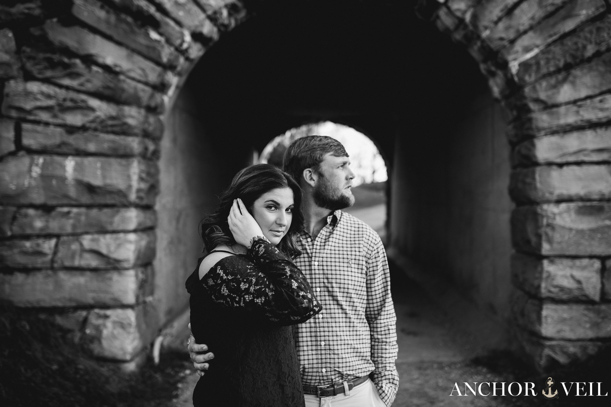 pulling her hair back as they sit near the tunnel during the Blue Ridge Mountains Engagement Session