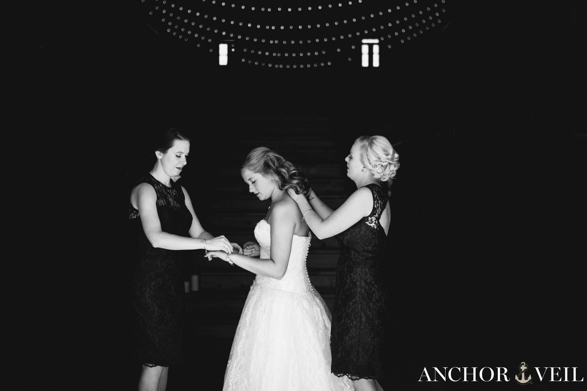 bridesmaids helping bride get jewelry on