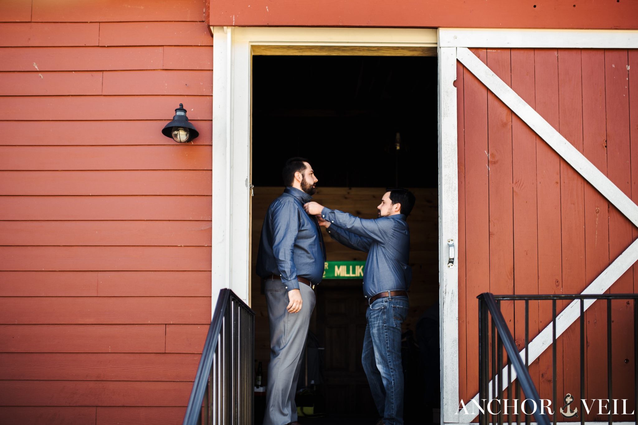 groomsmen helping groom get clothes on during the Millikan Farms Wedding
