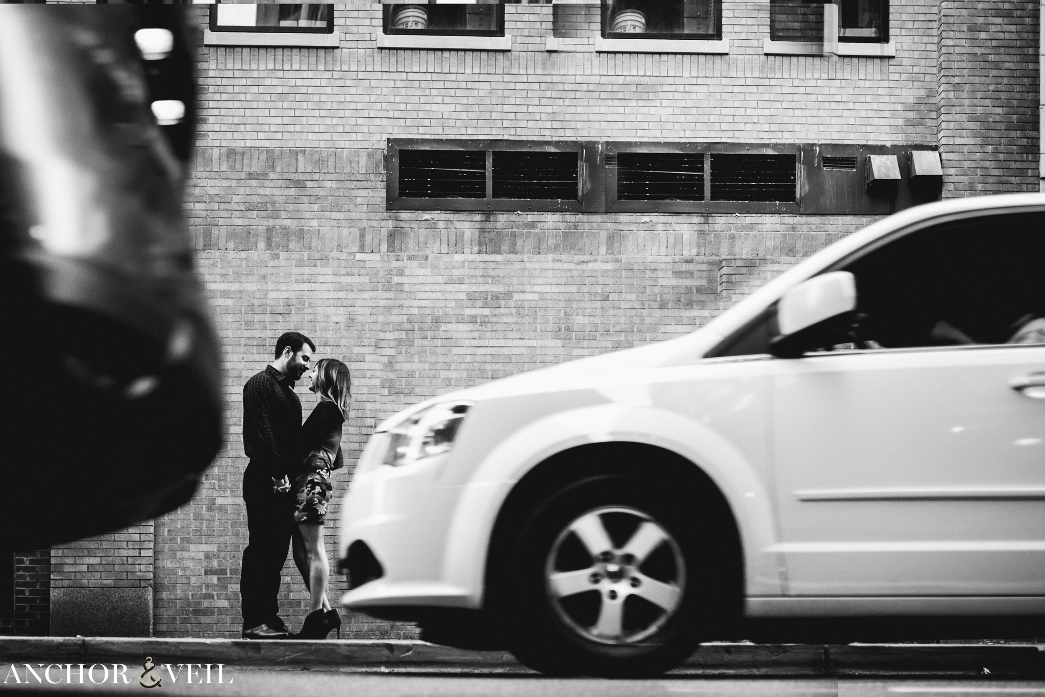 in between the cars as they hold each other during the Uptown Charlotte Engagement Session