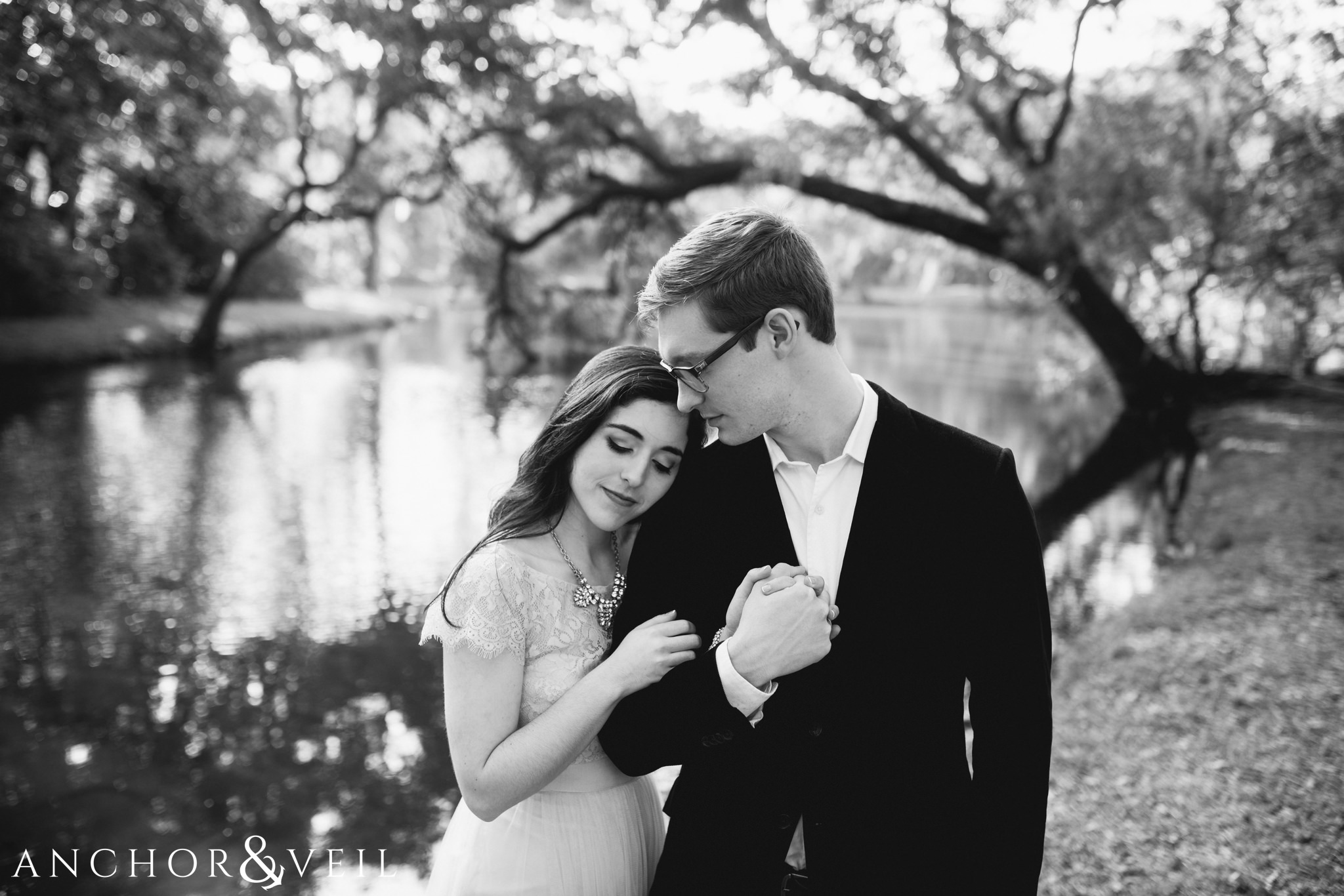 in front of the water in black and white during their legare waring house engagement session