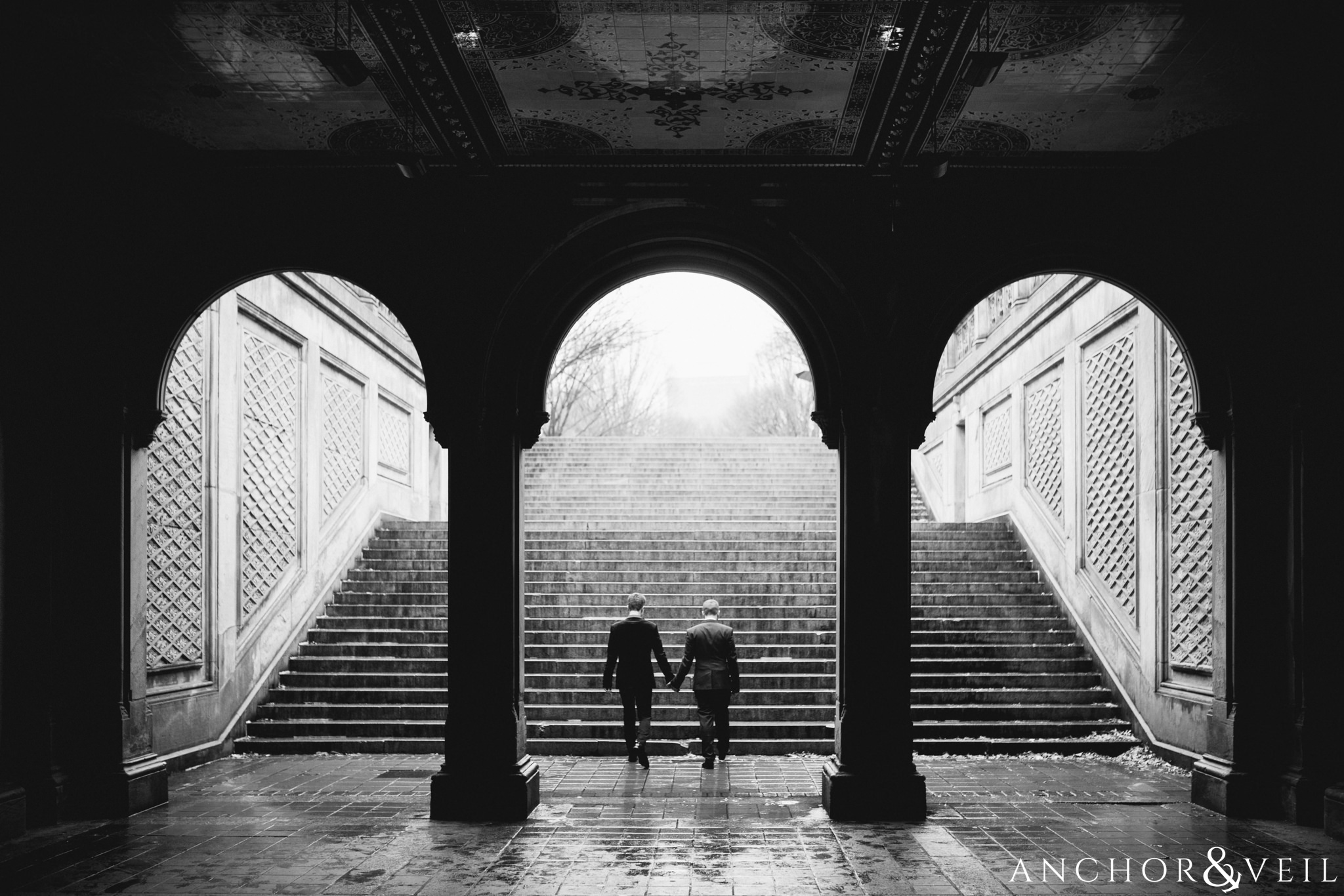 walking under the arches during their central park elopement in bethesda Terrace